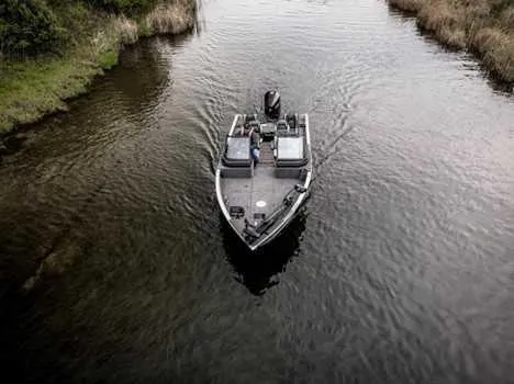 Slide: The Image of 2026 Lund 2075 IMPACT XS boat navigating a narrow waterway surrounded by greenery. - 15