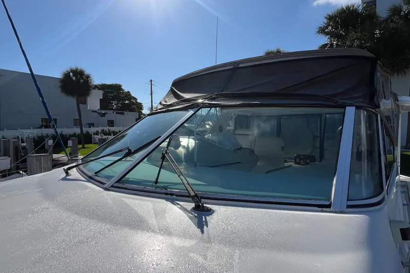 Slide: The Image of 2000 Cruisers Yachts 4450 Motor Yacht with sunlit windshield and marina backdrop. - 32