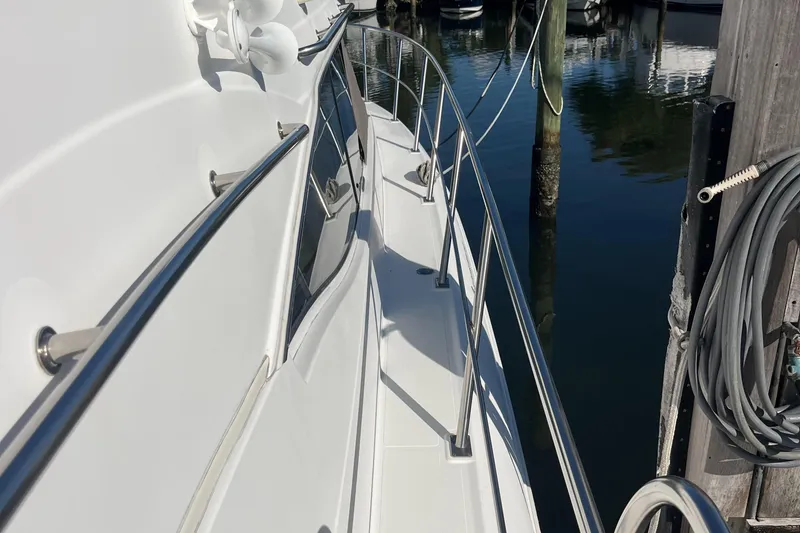 Slide: The Image of 2000 Cruisers Yachts 4450 Motor Yacht docked, showing sleek side deck and railing. - 14