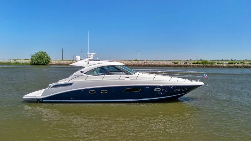 Slide: The Image of 2009 Sea Ray 43 Sundancer yacht cruising on a calm river under a clear blue sky. - 12