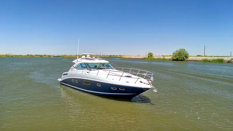Slide: The Image of 2009 Sea Ray 43 Sundancer yacht cruising on a calm river under a clear blue sky. - 13