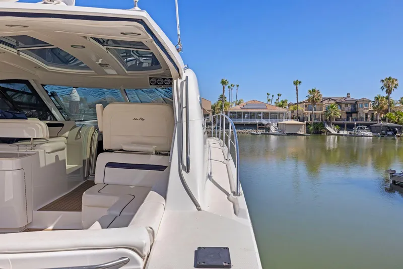 Slide: The Image of 2009 Sea Ray 43 Sundancer yacht docked by waterfront homes under clear blue sky. - 24
