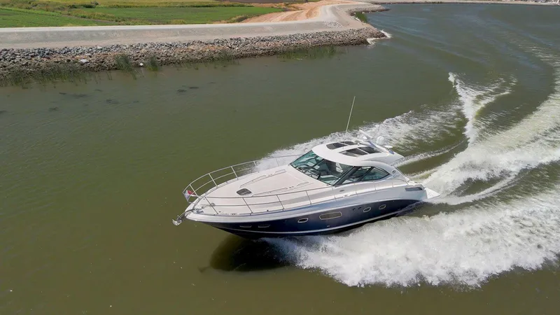 Slide: The Image of 2009 Sea Ray 43 Sundancer cruising on a calm waterway, creating a wake. - 8