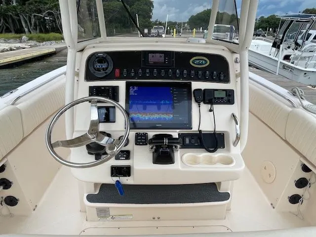 Slide: The Image of 2012 Grady-White 271 Canyon boat dashboard with steering wheel and navigation equipment. - 26