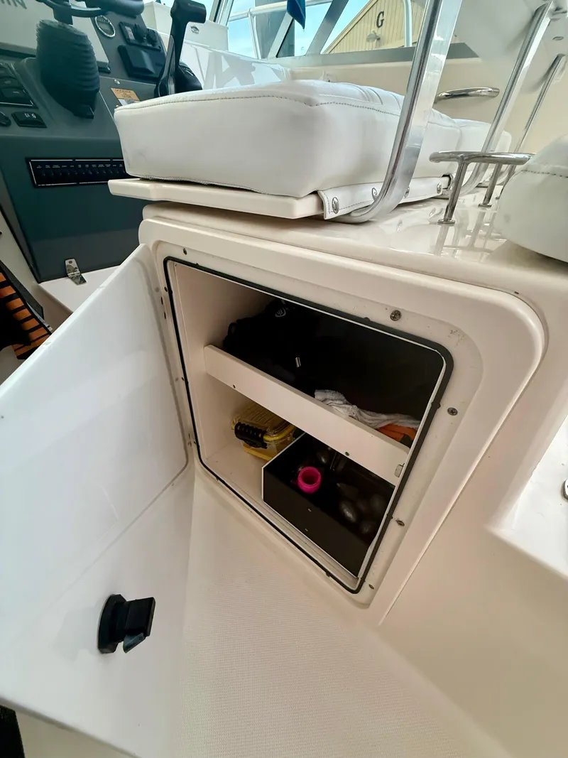 Slide: The Image of 2007 Pursuit 235 Denali LS boat storage compartment with various items inside. - 25