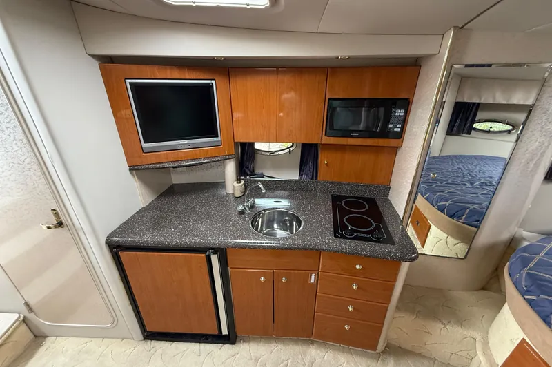 Slide: The Image of 2003 Formula 37 PC yacht kitchen with wood cabinets, sink, stove, microwave, and TV. - 16