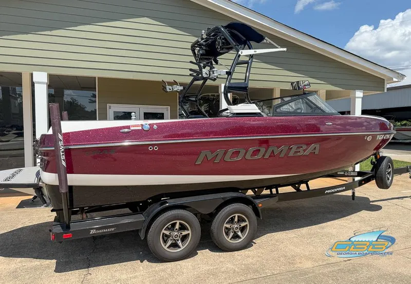 Slide: The Image of 2019 Moomba Craz boat on trailer, maroon color, parked outside a building. - 1