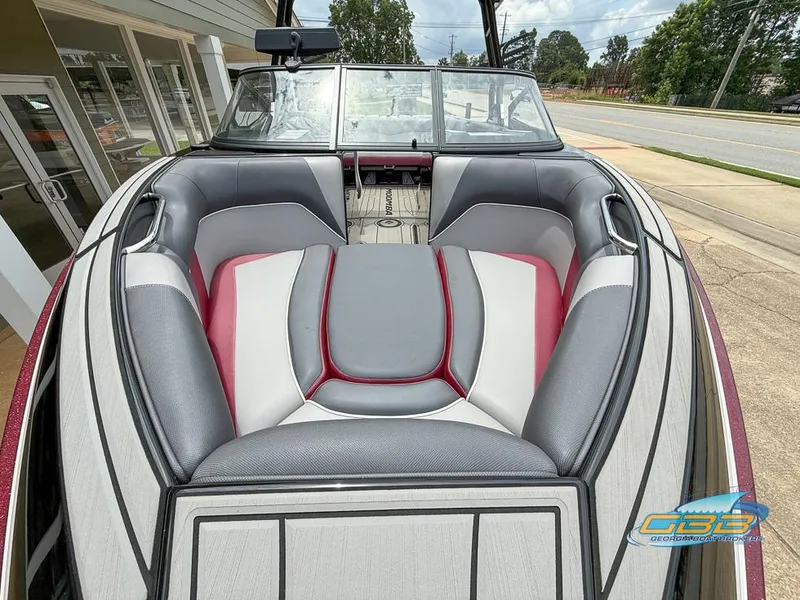 Slide: The Image of 2019 Moomba Craz boat interior with gray and red seating, parked near a building. - 13