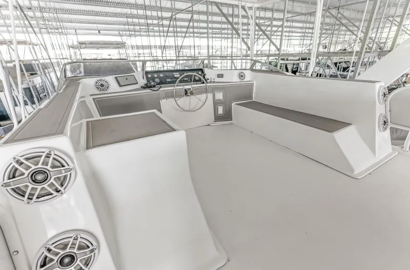 Slide: The Image of 1997 Sumerset 18 x 93 houseboat helm with seating and speakers in a covered marina. - 18