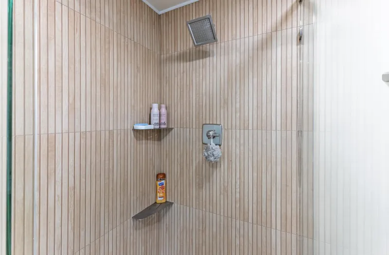 Slide: The Image of Modern shower with beige vertical tiles, featuring shelves and a square showerhead. Sumerset 18 x 93, 1997. - 27