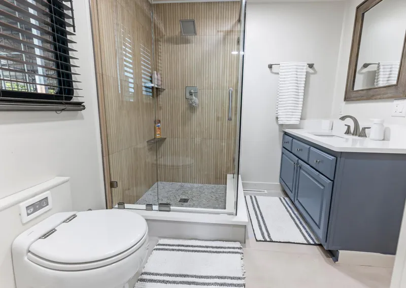 Slide: The Image of Modern bathroom with glass shower, blue vanity, and striped rugs in a 1997 Sumerset 18 x 93. - 30