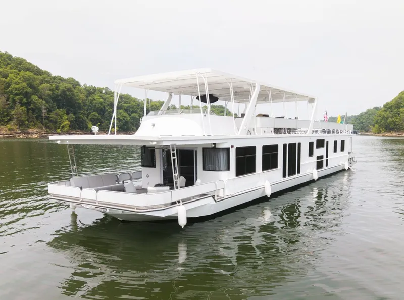 Slide: The Image of 1997 Sumerset 18 x 93 houseboat on a serene lake with lush green shoreline. - 5