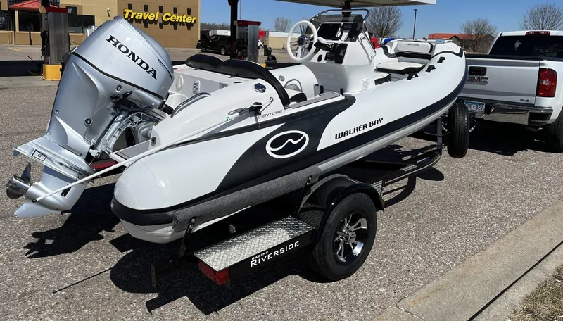 Slide: The Image of 2022 Walker Bay Venture 14 boat on trailer with Honda engine at travel center. - 14