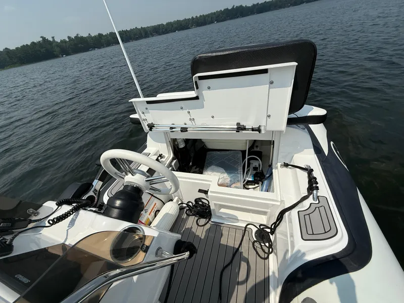 Slide: The Image of 2022 Walker Bay Venture 14 boat interior with open storage compartment on a lake. - 18