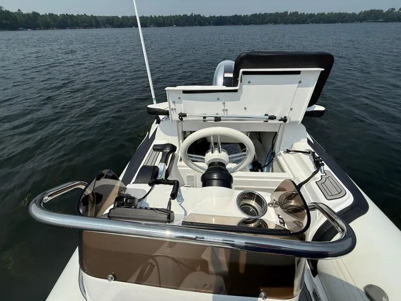 Slide: The Image of 2022 Walker Bay Venture 14 boat interior with steering wheel, cup holders, and open storage compartment. - 19