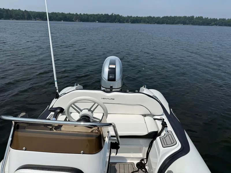 Slide: The Image of 2022 Walker Bay Venture 14 boat on a calm lake, featuring a sleek design and modern controls. - 22