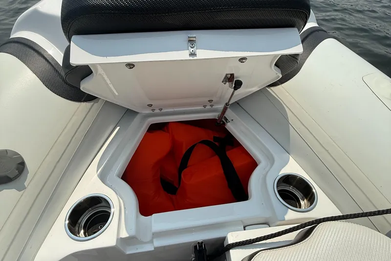 Slide: The Image of 2022 Walker Bay Venture 14 boat storage compartment with orange life jacket and cup holders. - 24