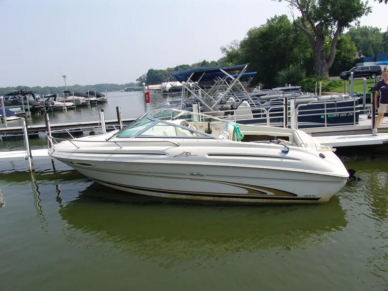 The Image of 2000 Sea Ray 215 Express Cruiser docked at a marina, surrounded by other boats. - 0