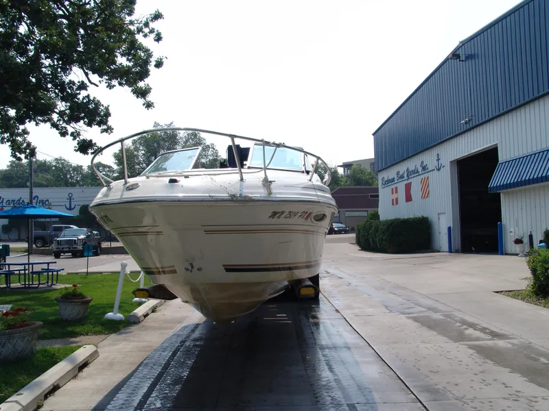 Slide: The Image of 2000 Sea Ray 215 Express Cruiser on trailer outside boatyard. - 11