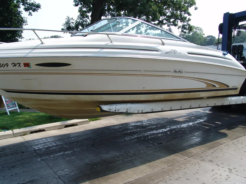 Slide: The Image of 2000 Sea Ray 215 Express Cruiser on a lift, side view, outdoors. - 12