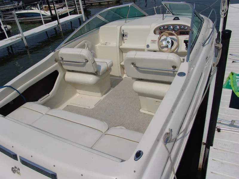 Slide: The Image of 2000 Sea Ray 215 Express Cruiser interior with white seating and dashboard, docked at marina. - 4
