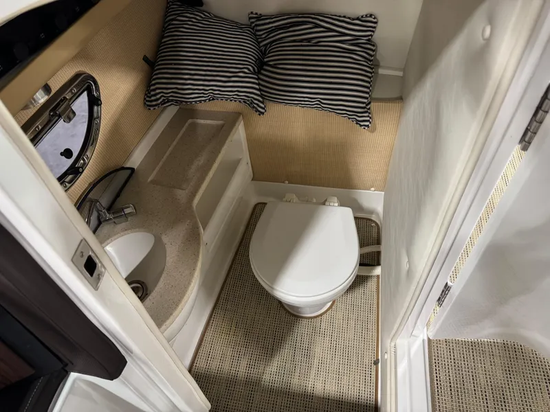 Slide: The Image of 2015 Cobalt 24 SD boat interior with toilet, sink, and striped cushions. - 10