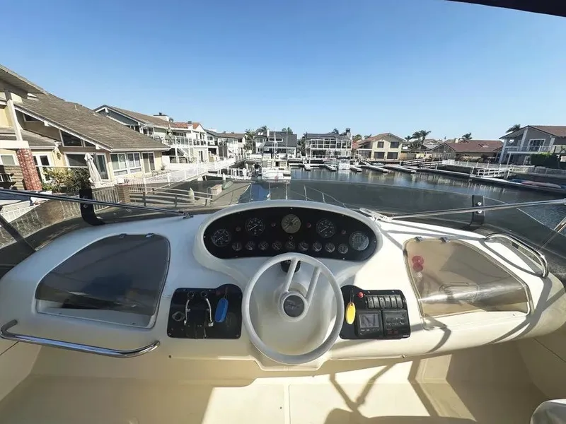 Slide: The Image of 1996 Azimut 54 yacht helm with marina view, showcasing controls and dashboard. - 13