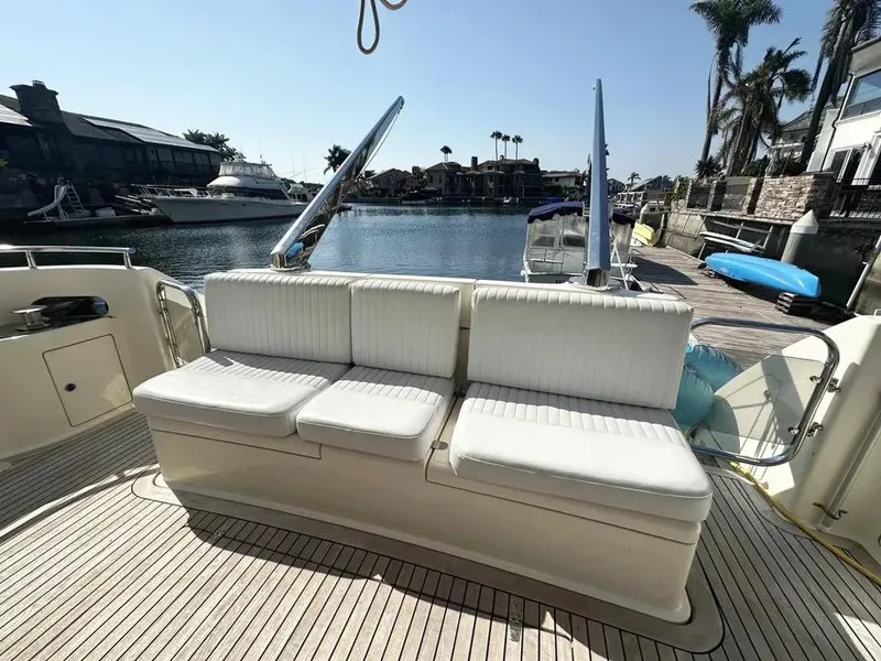 Slide: The Image of 1996 Azimut 54 yacht deck with white seating, docked by a serene waterfront. - 6