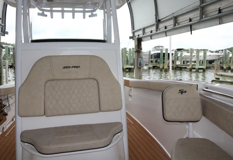 Slide: The Image of 2023 Sea Pro 259 DLX boat interior with beige seating and waterfront view. - 12