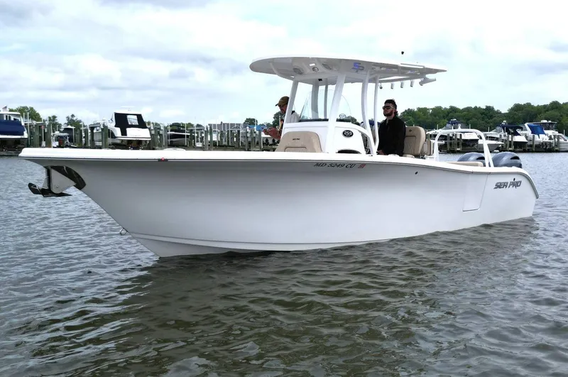 Slide: The Image of 2023 Sea Pro 259 DLX boat on water, docked at marina with people onboard. - 3