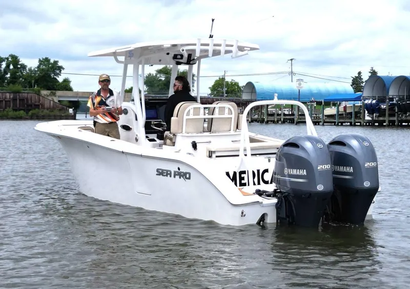 Slide: The Image of 2023 Sea Pro 259 DLX boat with dual Yamaha engines on a calm waterway. - 5