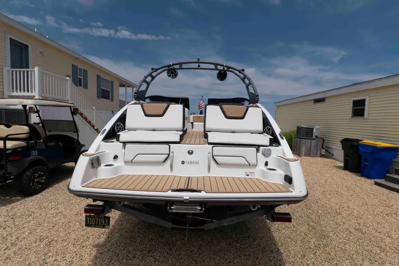 Slide: The Image of 2021 Yamaha Boats 252S parked on gravel, showcasing rear deck and seating. - 2