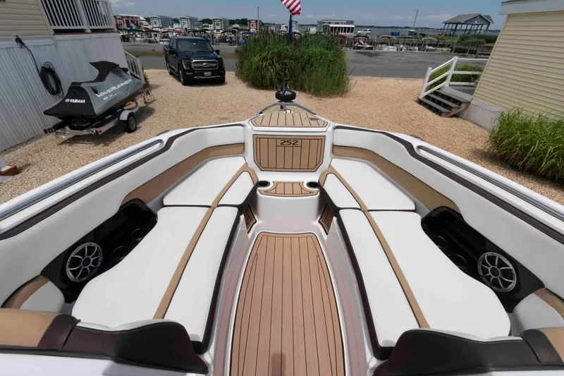 Slide: The Image of 2021 Yamaha Boats 252S interior with spacious seating and sleek design at a marina. - 5