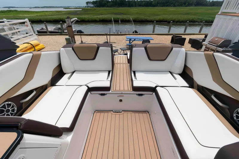 Slide: The Image of 2021 Yamaha Boats 252S interior with luxurious seating and sleek design, dockside view. - 8