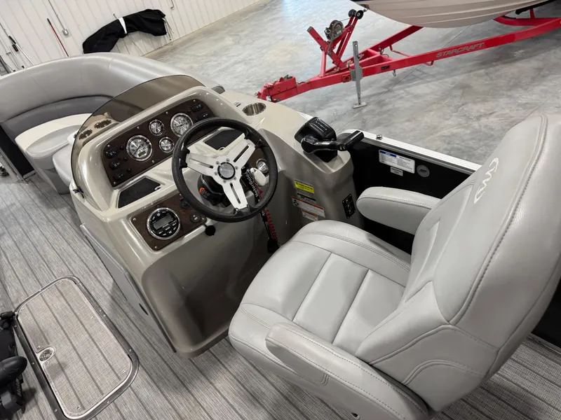 Slide: The Image of 2018 Manitou 23 Aurora LE boat interior with steering console and plush seating. - 6