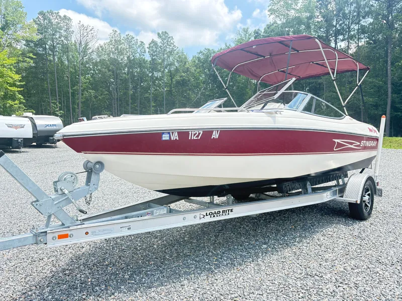 The Image of 1999 Stingray 190 LS boat on trailer, red and white, parked outdoors. - 2