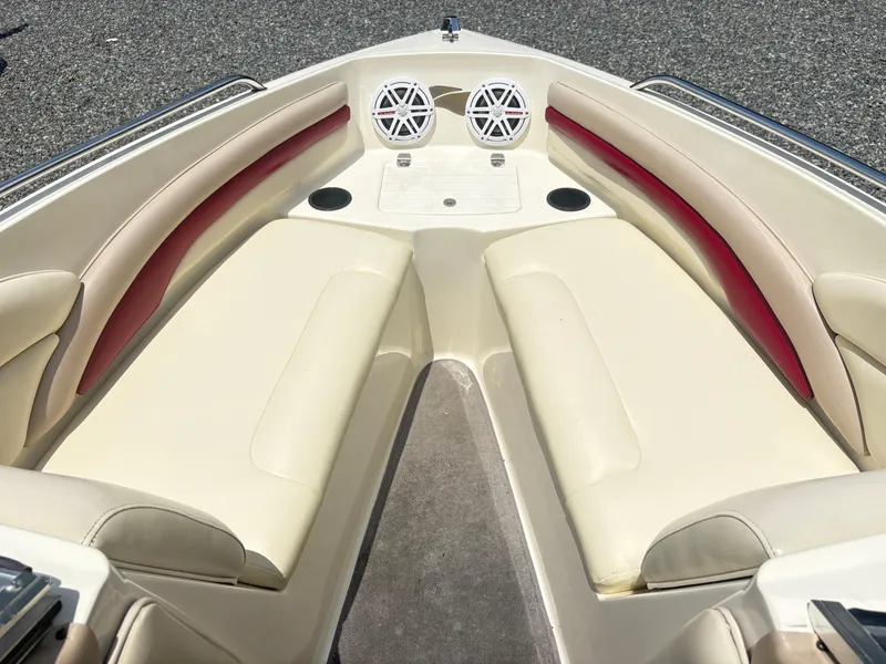 Slide: The Image of 1999 Stingray 190 LS boat interior with beige and red seating, dual speakers, and cup holders. - 9