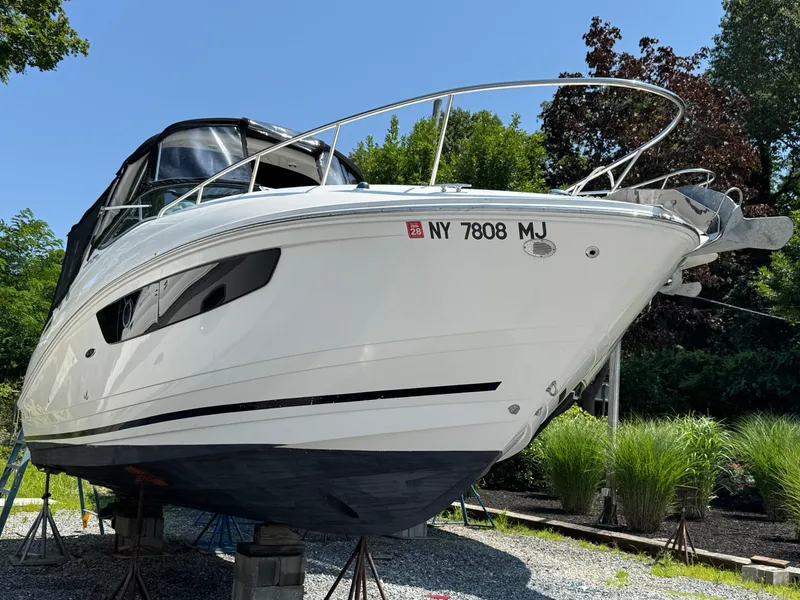 Slide: The Image of 2014 Sea Ray 280 Sundancer boat on stands, surrounded by greenery. - 1