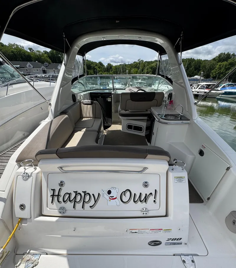 Slide: The Image of 2014 Sea Ray 280 Sundancer boat interior with seating and kitchenette at a marina. - 3