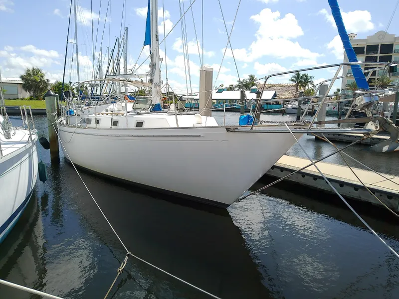 Slide: The Image of 1980 Whitby Yachts 42 docked at marina, clear sky, waterfront buildings in background. - 2