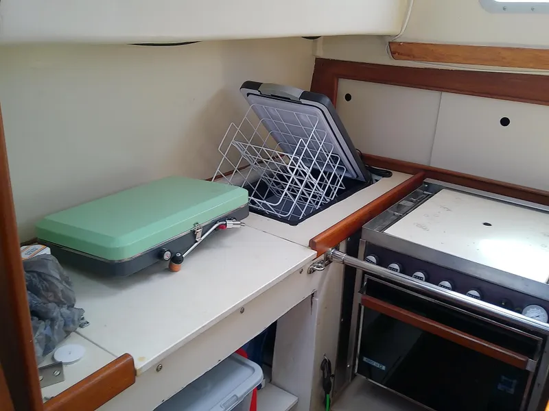 Slide: The Image of Interior of 1980 Whitby Yachts 42, featuring a compact kitchen area with stove and storage. - 30