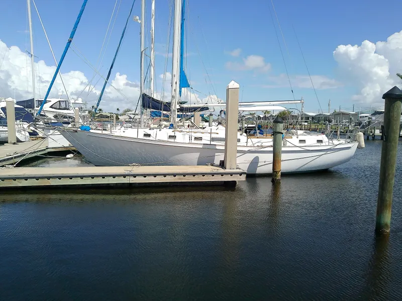 Slide: The Image of 1980 Whitby Yachts 42 sailboat docked, featuring open hatch and rigging, under a partly cloudy sky. - 4