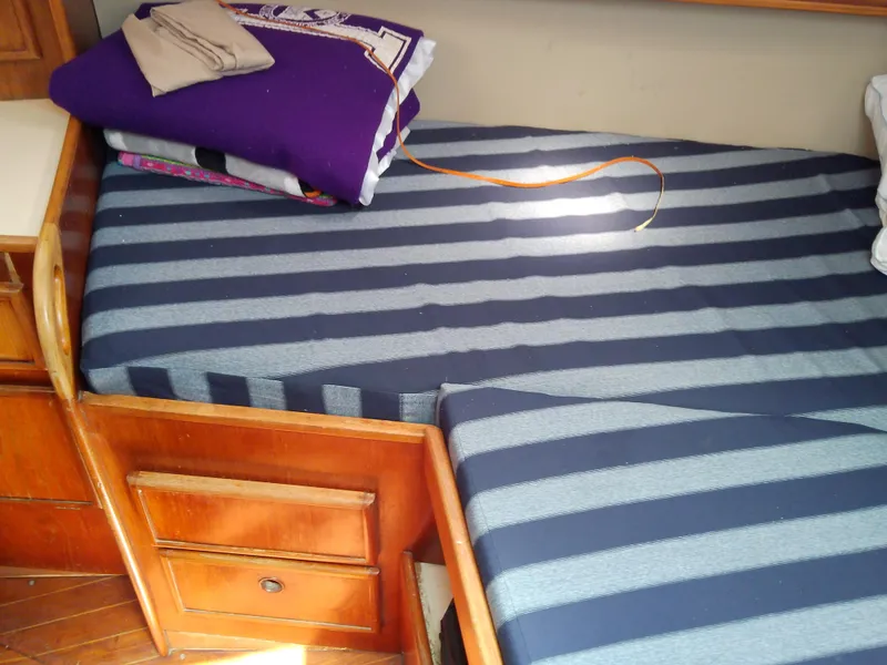 Slide: The Image of Interior cabin of 1980 Whitby Yachts 42, featuring a striped bed and wooden furnishings. - 43