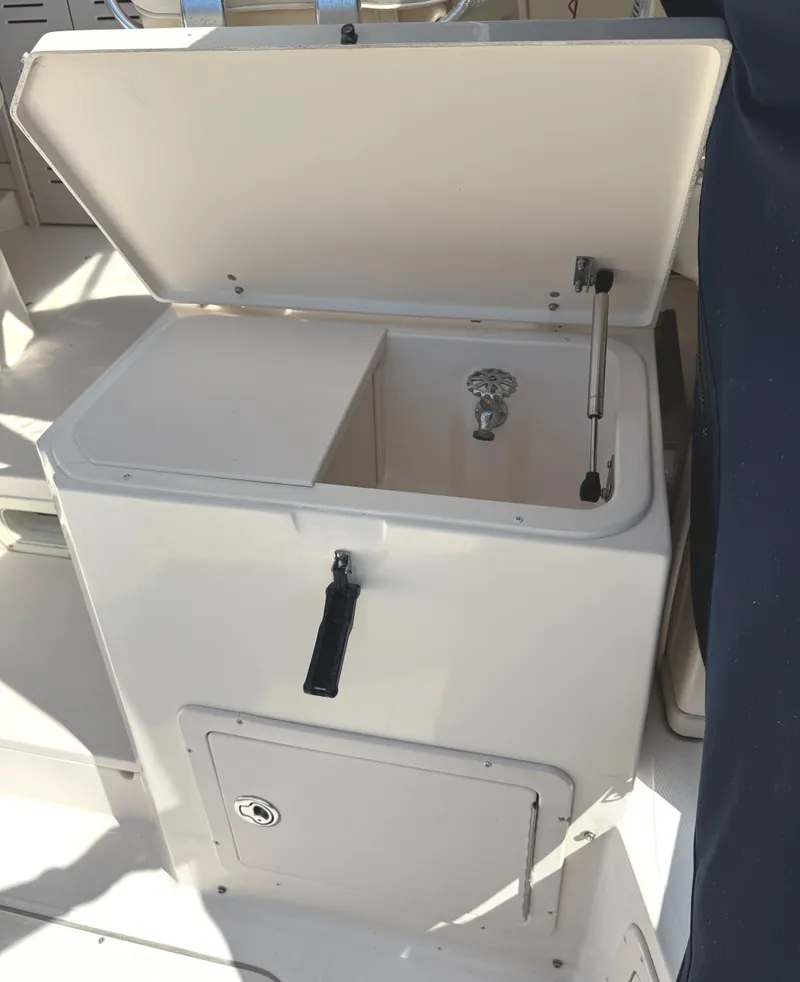 Slide: The Image of Open storage compartment on 2003 Grady-White Marlin 300 boat, featuring a faucet and secure latch. - 18