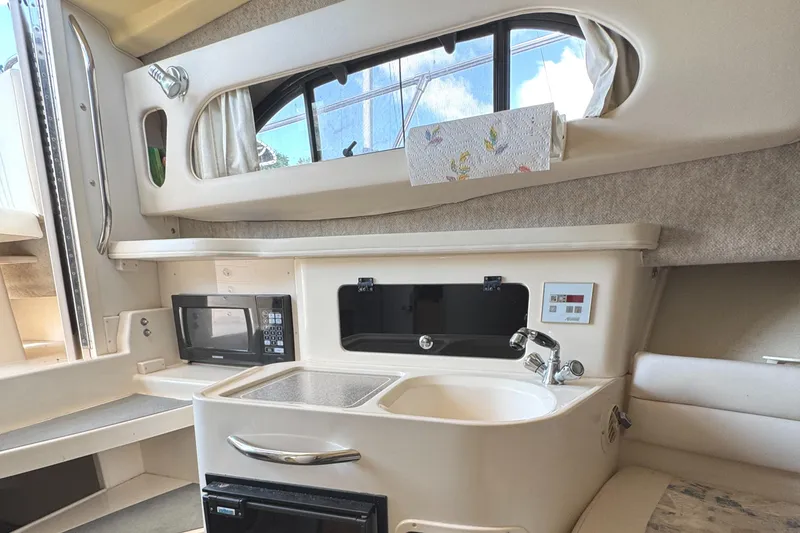 Slide: The Image of 2003 Grady-White Marlin 300 interior with kitchenette, featuring sink, microwave, and window view. - 27