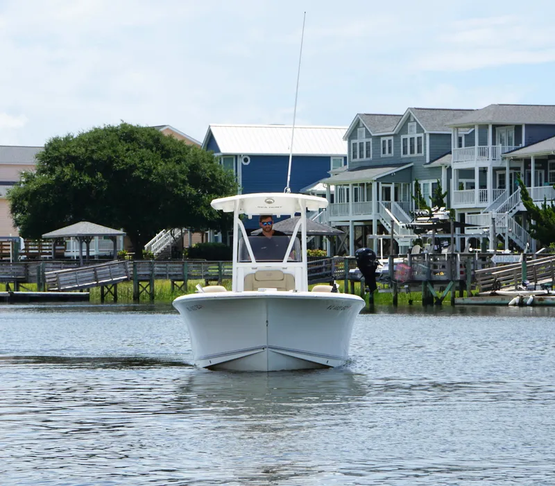 Slide: The Image of 2016 Sea Hunt Ultra 225 boat cruising near waterfront homes. - 4