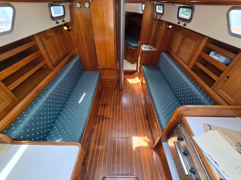 Slide: The Image of Interior of 1984 Bristol 31.1 sailboat with wooden finish and blue cushioned seating. - 1