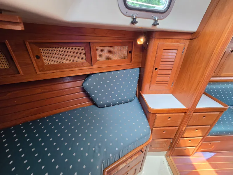 Slide: The Image of 1984 Bristol 31.1 yacht interior with wooden cabinetry and blue cushioned seating. - 11