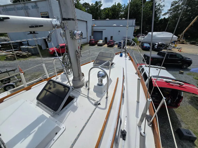 Slide: The Image of Deck view of a 1984 Bristol 31.1 sailboat at a marina with surrounding vehicles. - 13