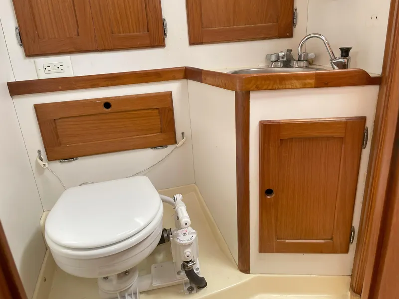 Slide: The Image of 1984 Bristol 31.1 yacht bathroom with wooden cabinets, sink, and marine toilet. - 19